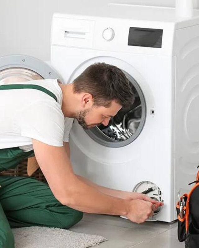 Técnico reparando una lavadora de carga frontal en un hogar